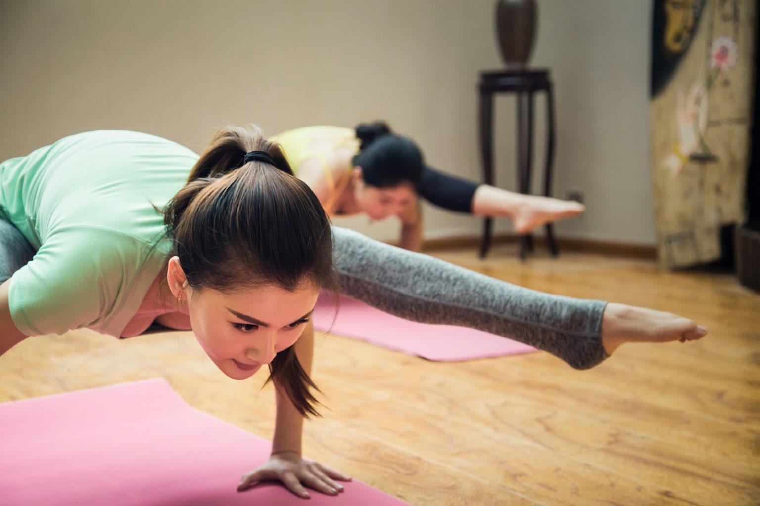 Grupo de alumnas en clase de pilates sobre mats, piso de madera con luz natural